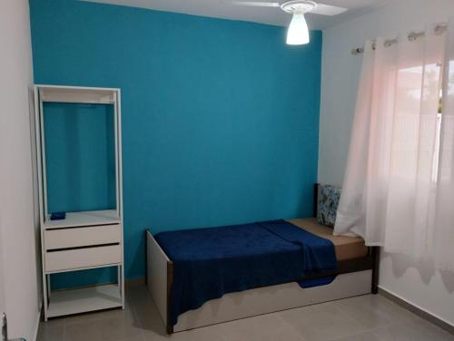 um quarto azul com uma cama e um espelho em Cantinho do descanso em Bertioga