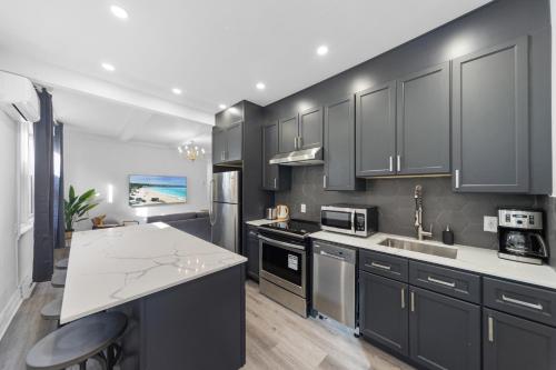 a kitchen with black cabinets and a white counter top at Modern and cozy 4 bedrooms sleep 12 in Montréal