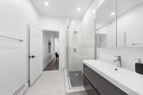 a white bathroom with a shower and a sink at Modern and cozy 4 bedrooms sleep 12 in Montreal