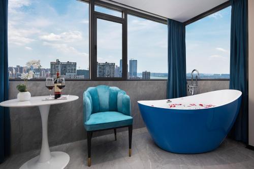 a bathroom with a tub and a table and a chair at MuMu Hotel Changsha in Changsha