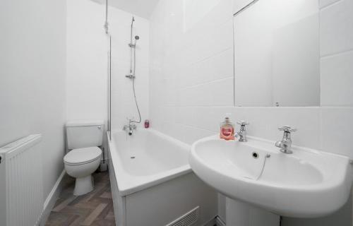 a white bathroom with a sink and a toilet at Modern 4-bedroom Apartment in Fulham, London in London