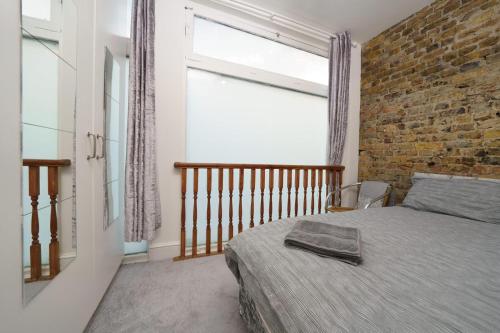 a bedroom with a bed and a brick wall at Modern 4-bedroom Apartment in Fulham, London in London