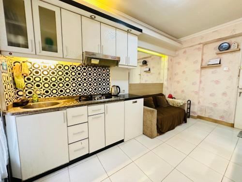 eine Küche mit weißen Schränken und einem Sofa in einem Zimmer in der Unterkunft 2 Bedrooms Apartment Strategic Location Affordable for All in Jakarta