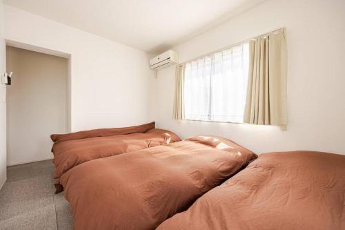 two beds in a room with a window at Torinosu in Jōnouchi