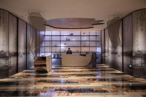 a man standing at a desk in a lobby at Hotel Indigo Wuxi Taihu New City in Wuxi