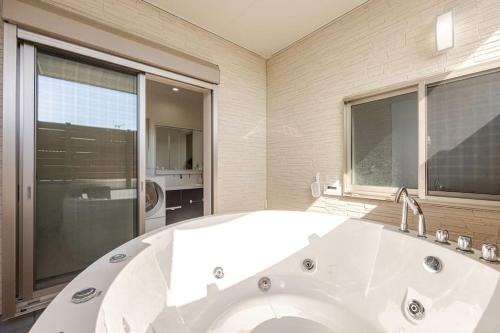 a large white bath tub in a bathroom with a window at Torinosu in Jōnouchi