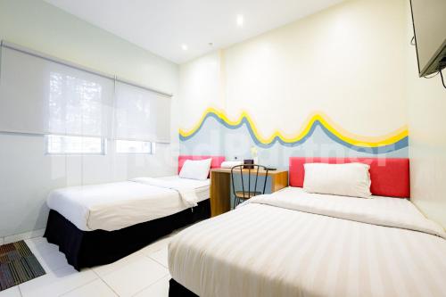 um quarto com 2 camas e uma cabeceira colorida em Hotel Capital Cikokol RedPartner em Kebonnanas