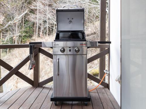 a grill on a deck with a view of trees at Kurokawa Mori No Kiki in Minamioguni