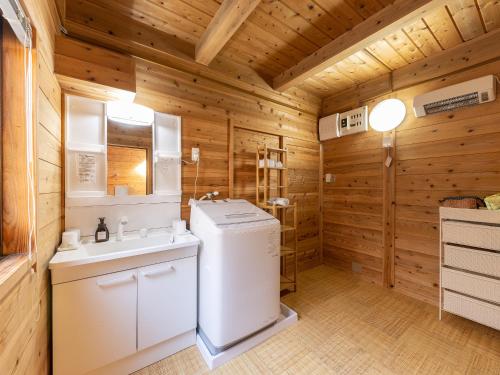 a bathroom with a washer and dryer in a cabin at Kurokawa Mori No Kiki in Minamioguni