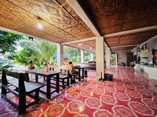 un restaurante con mesas y sillas en un suelo de baldosas rojas en Lae Tawan Bungalow, en Koh Chang