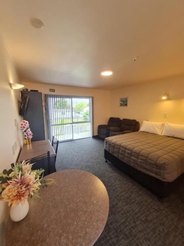 a bedroom with a bed and a couch and a table at Avenue Heights Motel in Whangarei