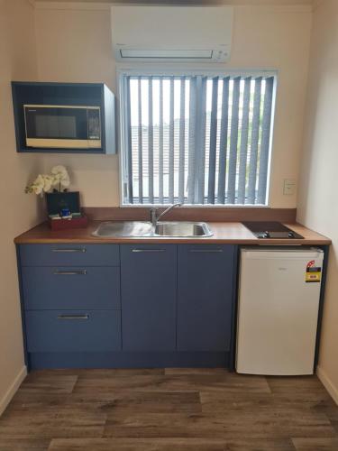 a small kitchen with a sink and a microwave at Avenue Heights Motel in Whangarei
