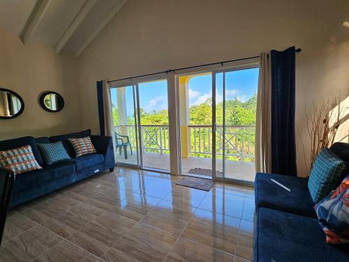 sala de estar con sofá y puerta corredera de cristal en Royal Escape - 2 en Anse La Raye