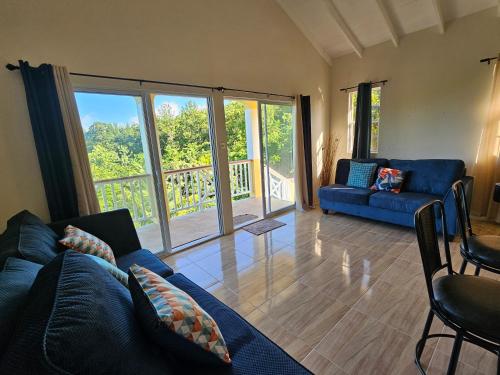 a living room with a blue couch and glass doors at Royal Escape - 2 in Anse La Raye