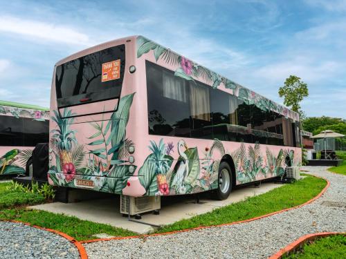 a pink bus is parked in a parking lot at The Bus Collective in Singapore