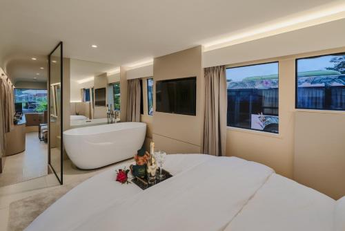 a bedroom with a large white bed and a bath tub at The Bus Collective in Singapore