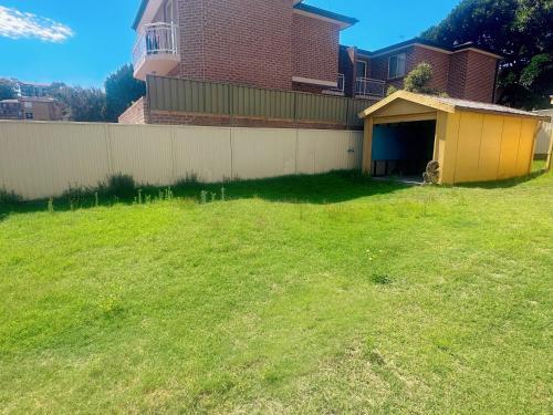 um quintal com uma cerca e uma garagem amarela em three bedroom house within walking distance to light rail station em Sidney