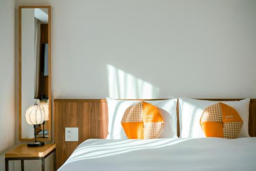 Schlafzimmer mit einem Bett mit weißer Bettwäsche und orangefarbenen Kissen in der Unterkunft OMO5 Kyoto Sanjo by Hoshino Resorts in Kyoto