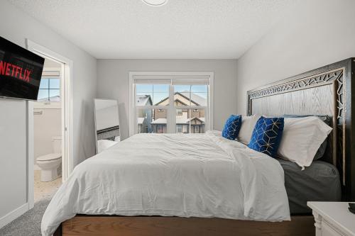Un dormitorio con una gran cama blanca y una ventana en Newly Built Family Townhome, Sleeps 12 Comfortably, en Airdrie