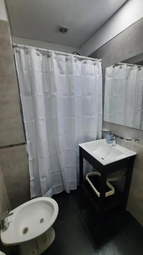 a bathroom with a sink and a white shower curtain at Departamento en el Centro in Puerto Madryn