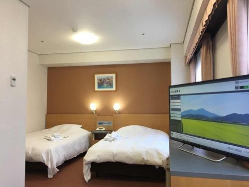 um quarto de hotel com duas camas e uma televisão de ecrã plano em Hotel Alpha-One Sakata em Sakata