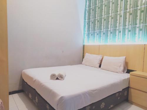 a bedroom with a bed with two shoes on it at RedDoorz at DeAmartaLoka Colomadu Solo in Tjolomadu