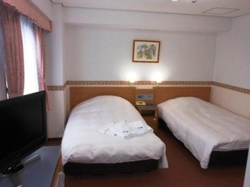 鶴岡市にあるホテルアルファーワン鶴岡のベッド2台、薄型テレビが備わるホテルルームです。