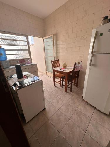eine Küche mit einem Tisch und einem weißen Kühlschrank in der Unterkunft Apartamento na rua do Santuário in Aparecida