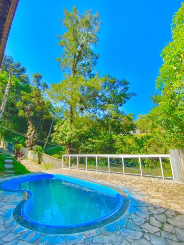 a blue pool in a yard with a white fence at Casa Monte Verde in Petrópolis