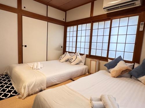 two beds in a room with windows at Yuyu House Kohama Teru - Vacation STAY 15334 in Osaka