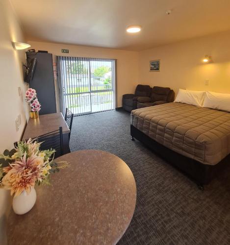 a bedroom with a bed and a couch and a table at Avenue Heights Motel in Whangarei