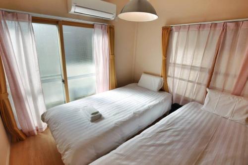 um pequeno quarto com 2 camas e uma janela em Edogawa Japanese Style Apartment 201 has direct access to Akihabara and Shinjuku, with convenient transportation and free WiFi em Tóquio