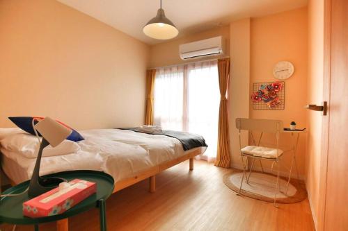 a bedroom with a bed and a chair and a window at Edogawa Japanese Style Apartment 201 has direct access to Akihabara and Shinjuku, with convenient transportation and free WiFi in Tokyo