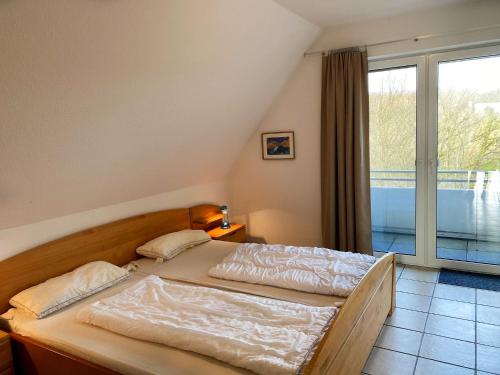 een slaapkamer met een bed en een groot raam bij Haus-Hooge-Whg-04 in Sankt Peter-Ording