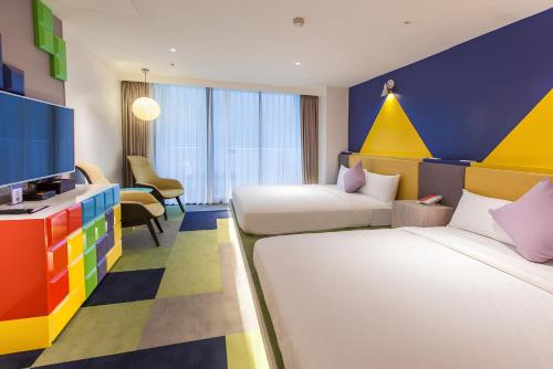 a colorful hotel room with two beds and a tv at HOTEL CHAM CHAM - Tainan in Nanxi