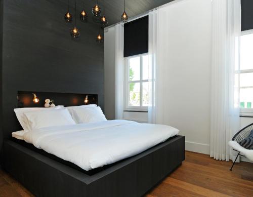 a bedroom with a large bed with white sheets at Het Raadhuys - design B&B in Kessel