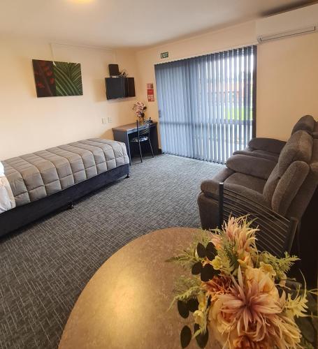 a hotel room with a bed and a couch and a table at Avenue Heights Motel in Whangarei