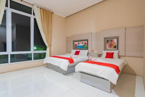 two beds in a room with a window at RedDoorz Resort Premium @ Sangkan Hurip Kuningan in Kuningan