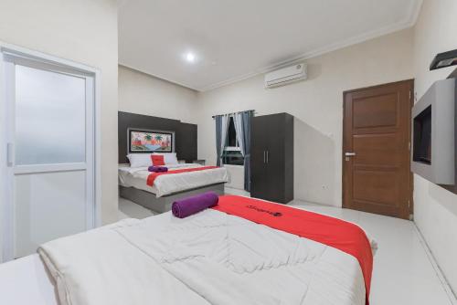 a bedroom with two beds and a television in it at RedDoorz Resort Premium @ Sangkan Hurip Kuningan in Kuningan