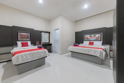 a bedroom with two beds with red pillows at RedDoorz Resort Premium @ Sangkan Hurip Kuningan in Kuningan