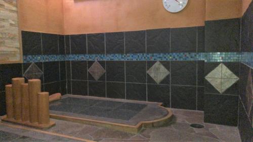 baño con bañera con reloj en la pared en Kanazawa City Hotel en Kanazawa