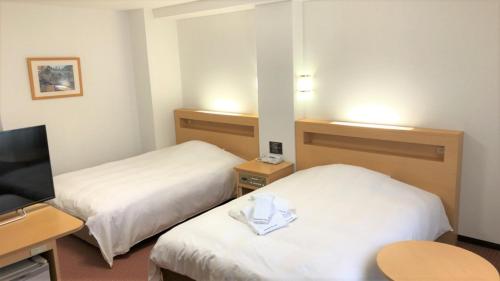 a hotel room with two beds and a desk at Kanazawa City Hotel in Kanazawa