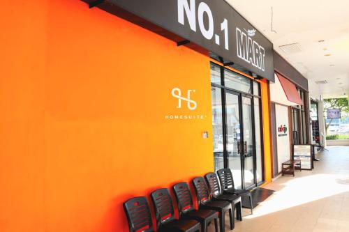 an orange wall with black chairs in front of a store at Homesuite' Home at The Loft in Kota Kinabalu