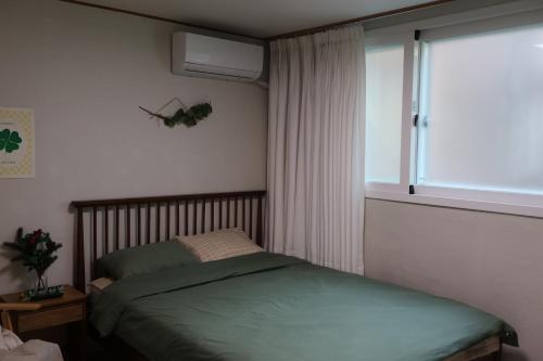 um quarto com uma cama verde e uma janela em Clover Stay, 2BR,1BA,mapo, free-wifi, em Seul