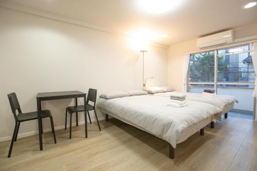 a bedroom with two beds and a table and a window at walk to JR Yoyogi sta.-DSYE in Tokyo