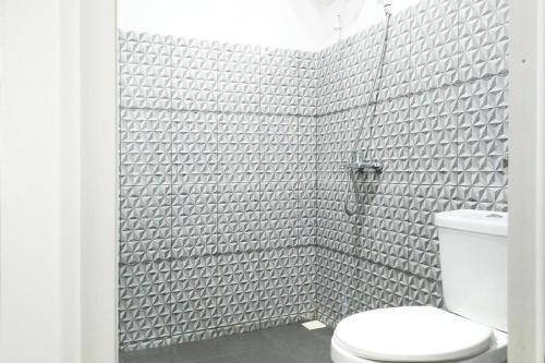 a white bathroom with a toilet and a shower at Urbanview Hotel Nerine's Glamping Village Cipanas by RedDoorz in Barukupa