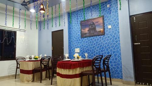 un comedor con 2 mesas y una pared azul en VISWAMURTI RESORTS, en Chālsa Mahābāri