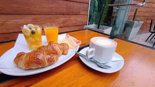 una mesa con un plato de bollería y una taza de zumo de naranja en Hostería Suites Del Centro en Santa Rosa de Calamuchita