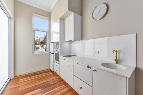 a kitchen with white cabinets and a clock on the wall at Aloha Central Platinum Apartments in Mount Gambier