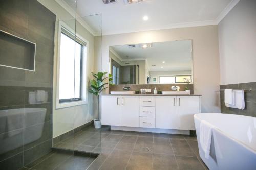 a bathroom with a tub and a sink and a mirror at Amaroo in Bright